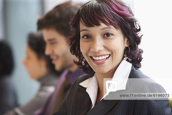 Smiling Hispanic businesswoman in office with co-workers