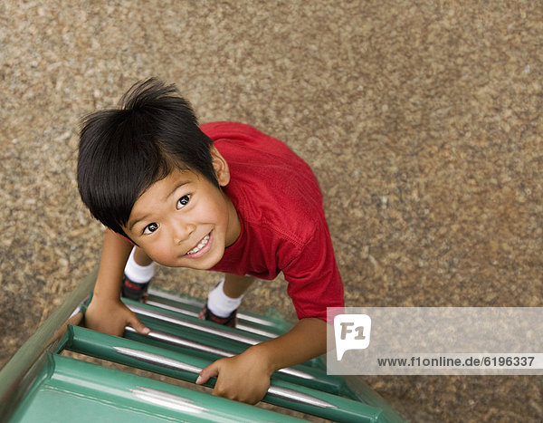 Asian boy climbing ladder on playground