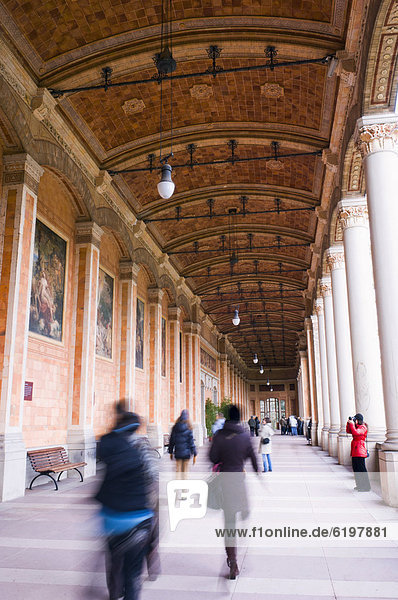 People walking underneath ornate portico