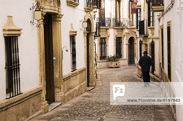 Man walking down cobblestone alley in quaint village