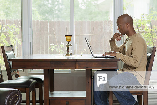 Black man using laptop at table