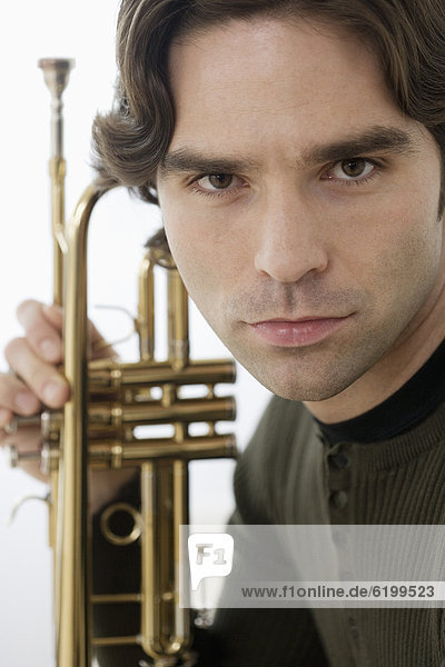 Close up of Hispanic man holding trumpet