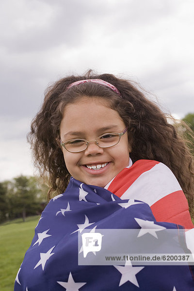 Hispanic girl wrapped in American flag