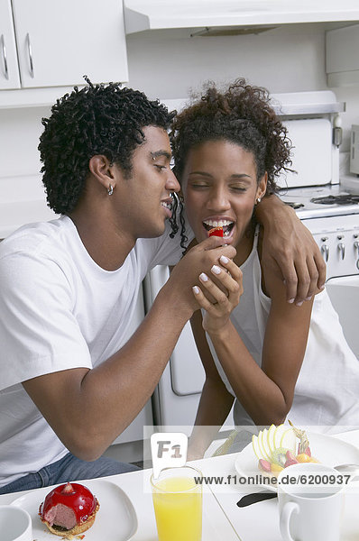 African man feeding fruit to girlfriend