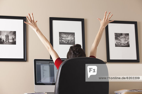 Caucasian woman cheering at desk in home office