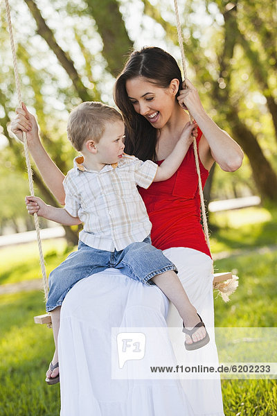 Caucasian mother and son swinging together
