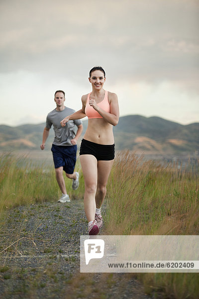 Caucasian couple running together on remote path