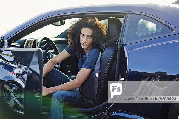 Mixed race teenager sitting in car