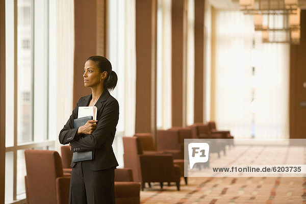 African businesswoman holding paperwork in hotel lobby