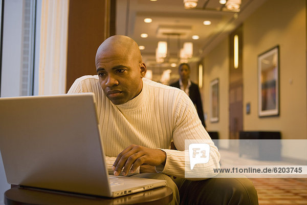 African businessman working on laptop in corridor