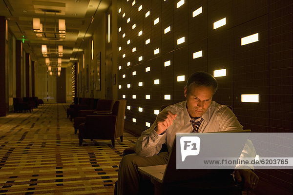 Businessman working on laptop late in lobby