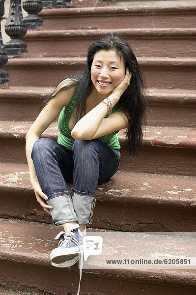 Asian woman sitting on front steps