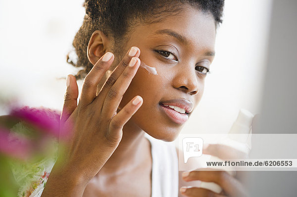 Black woman putting on face lotion