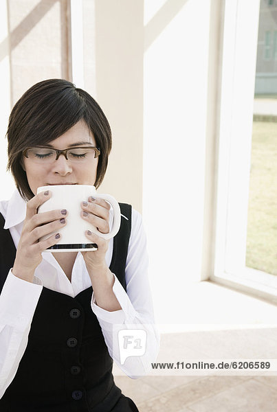 Hispanic businesswoman drinking coffee outdoors