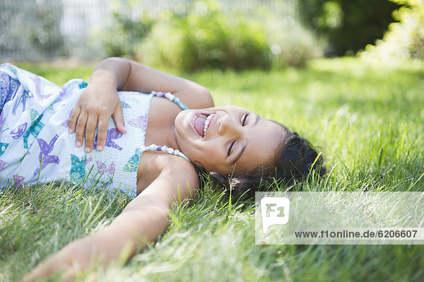 Laughing Hispanic girl laying in grass
