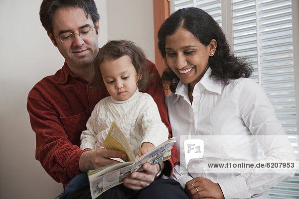 Parents reading book to daughter