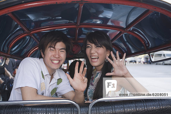 Asian couple in taxi waving