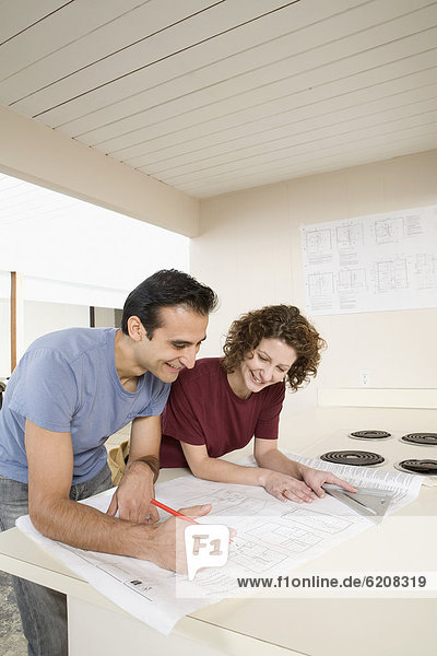 Couple looking at blueprint in kitchen