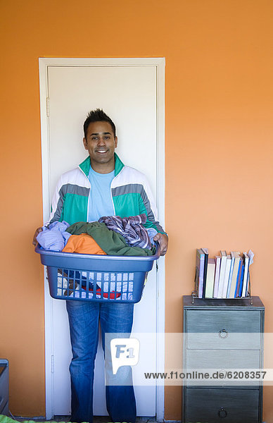 Mixed race man carrying laundry basket