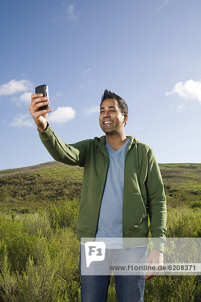 Mixed race man taking photo with cell phone