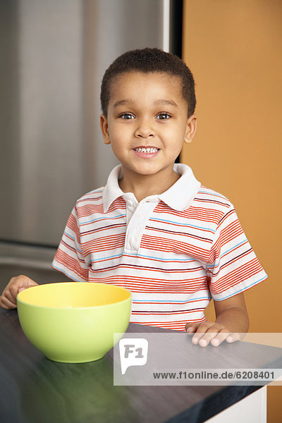 Mixed race boy with bowl in kitchen