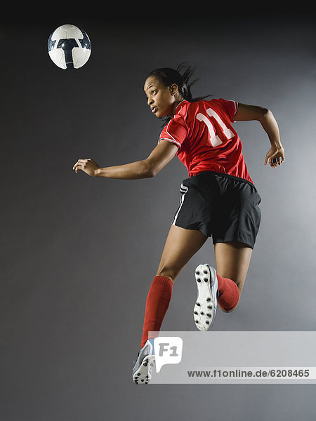 Mixed race soccer player in air with soccer ball