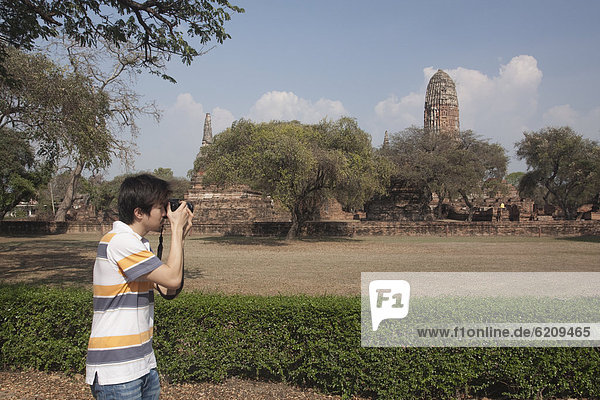 Asian man photographing outside temple