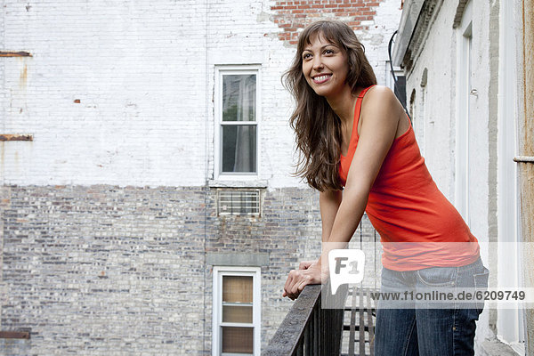 Mixed race woman leaning on fire escape railing