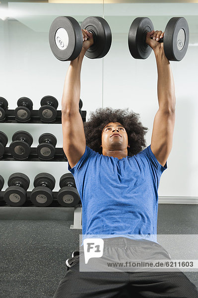 Black man lifting dumbbells in gym
