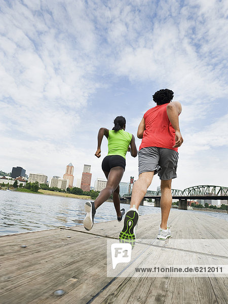 Couple running on urban boardwalk along river