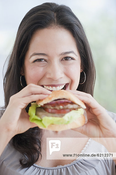 Hispanic woman eating hamburger