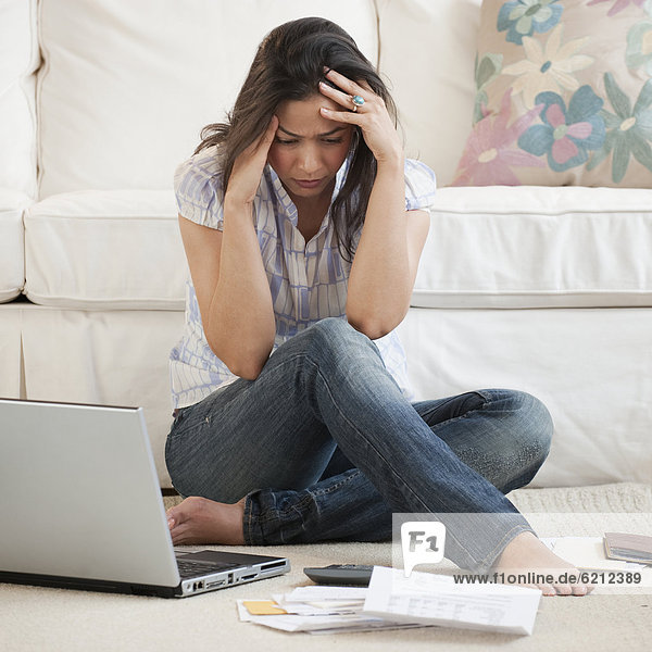 Hispanic woman looking at bills with head in hands