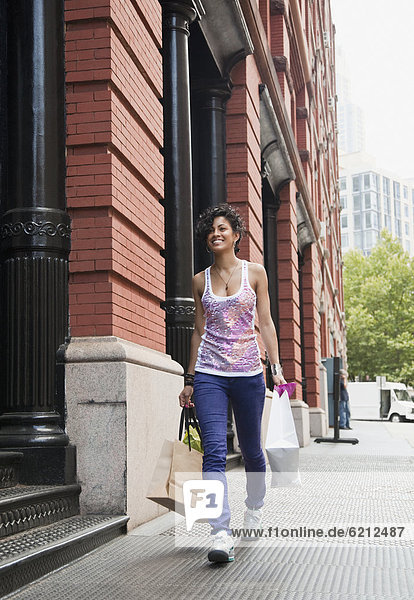 Mixed race woman carrying shopping bag on urban sidewalk