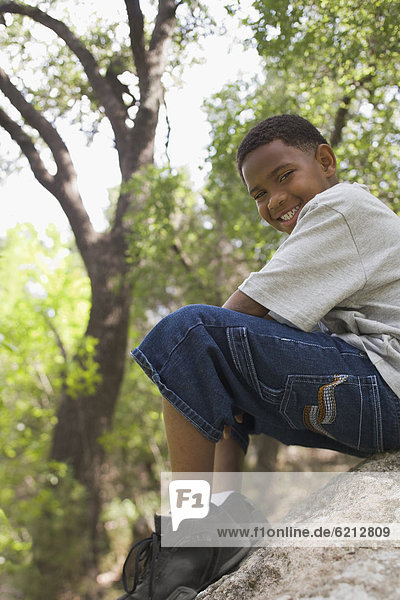 African boy sitting on rock in park