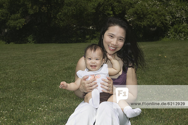 Chinese mother holding baby in park