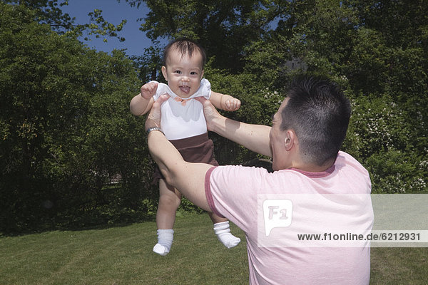 Chinese father lifting baby in park