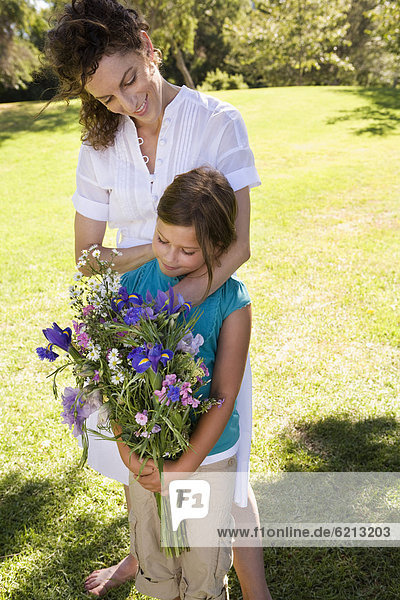 Mother standing with daughter holding flowers