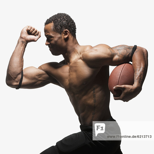 Bare chested football player running with football
