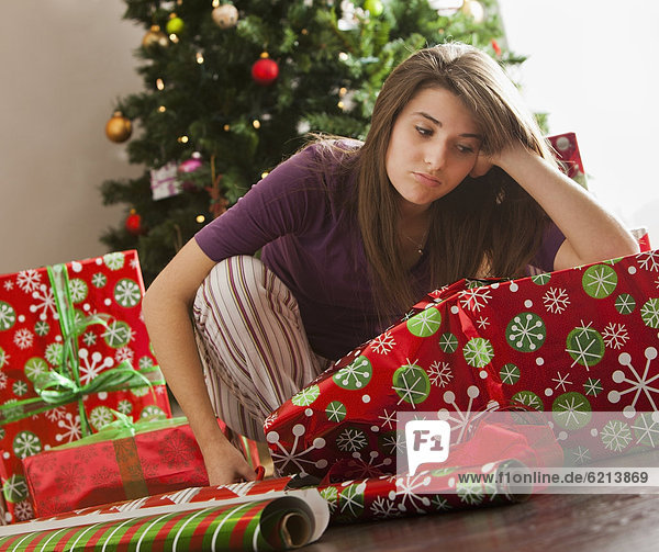 Bored Caucasian woman wrapping Christmas gifts