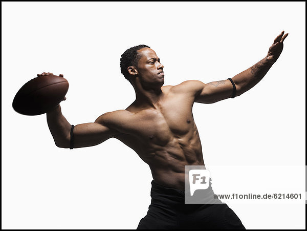 Bare chested football player throwing football