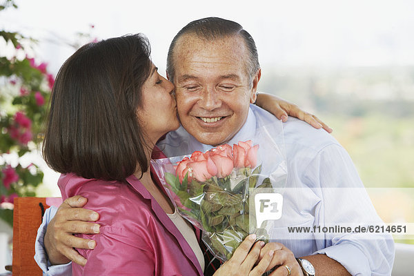 Hispanic man giving wife flowers