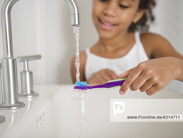 Mixed race girl brushing her teeth