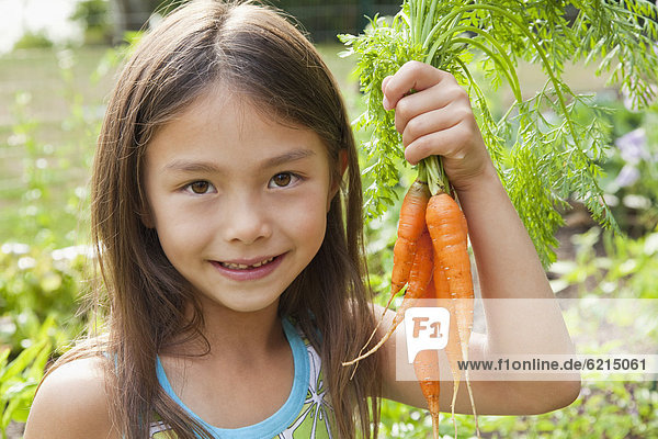 Mixed race girl holding carrots