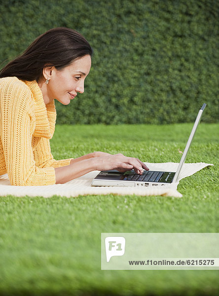 Hispanic woman using laptop in park