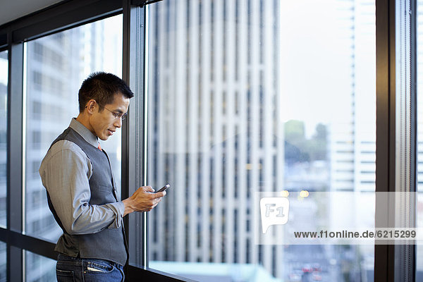 Mixed race businessman using cell phone in office