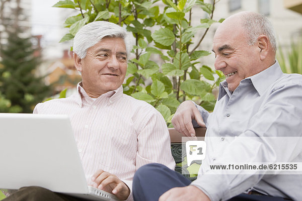 Senior Hispanic friends looking at laptop