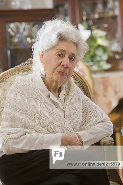 Senior Hispanic woman sitting in chair