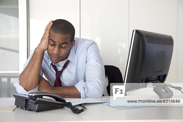 Tired Black businessman sitting at desk