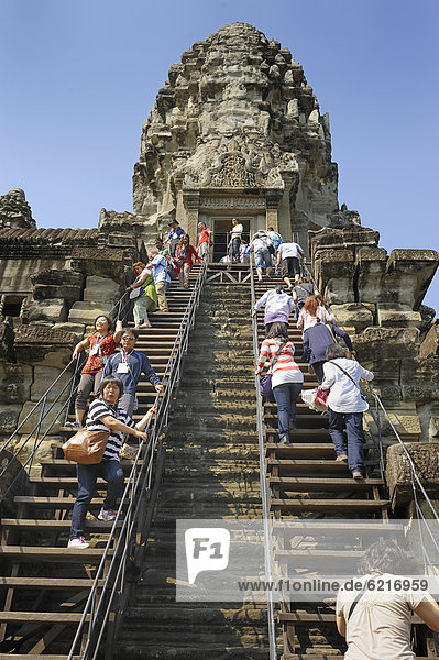 Tourists climbing a steep staircase  Angkor Wat temple  Cambodia  South East Asia