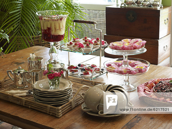 Stilvoll eingedeckter Kaffeetisch in romantischem Ambiente mit Früchtepudding und Petit four